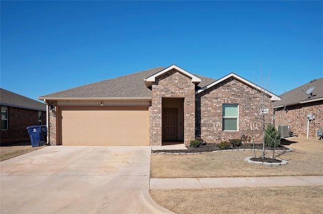 ranch-style house featuring an attached garage, cooling unit, brick siding, a shingled roof, and driveway