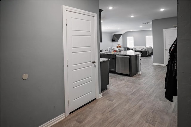 kitchen featuring light stone counters, light wood finished floors, stainless steel dishwasher, open floor plan, and baseboards