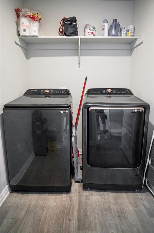 clothes washing area with laundry area, light wood finished floors, and washer and clothes dryer