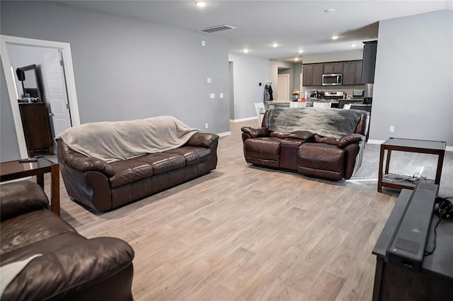 living room featuring light wood-style flooring, recessed lighting, visible vents, and baseboards