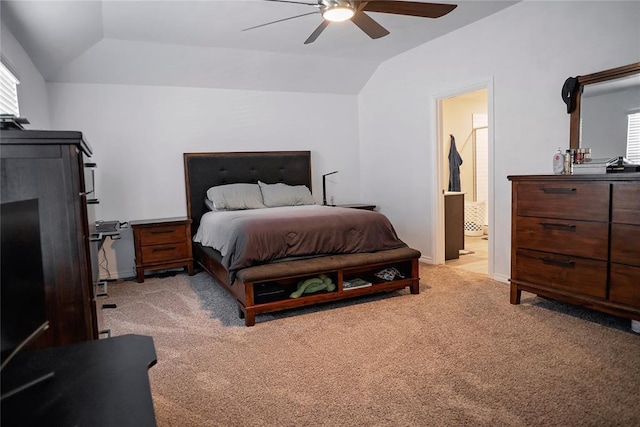 bedroom featuring baseboards, a ceiling fan, light colored carpet, ensuite bath, and vaulted ceiling