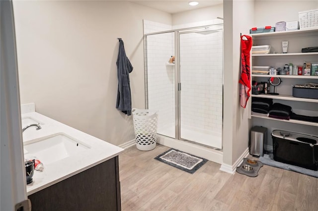 bathroom featuring a sink, double vanity, wood finished floors, and a shower stall