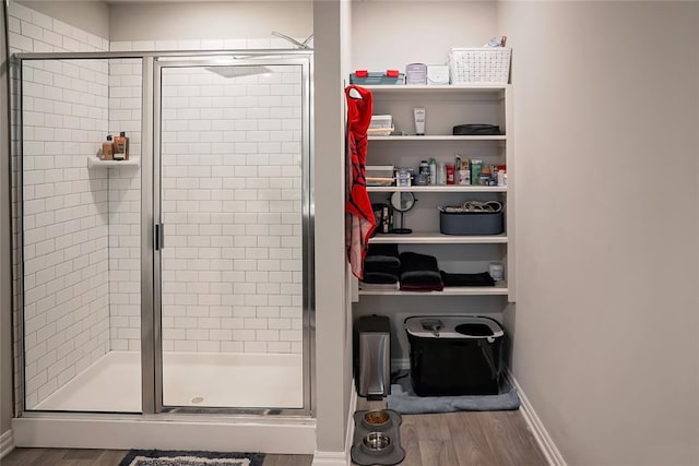 full bath featuring a shower stall, baseboards, and wood finished floors