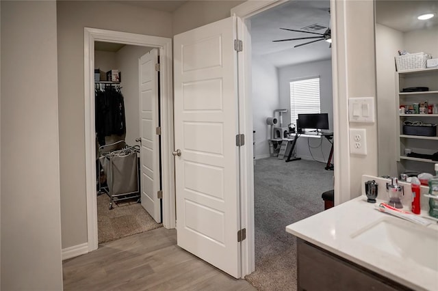 bathroom featuring ceiling fan, a sink, wood finished floors, visible vents, and baseboards