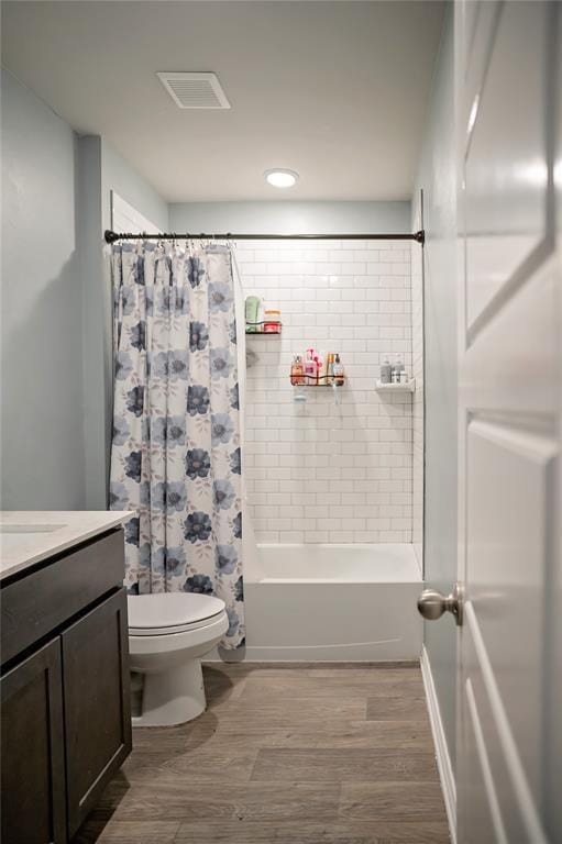 full bathroom with visible vents, toilet, wood finished floors, shower / bath combination with curtain, and vanity