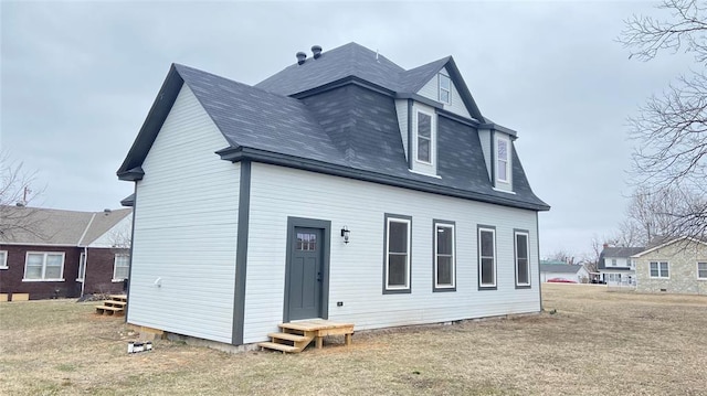 back of property featuring entry steps, a yard, and roof with shingles