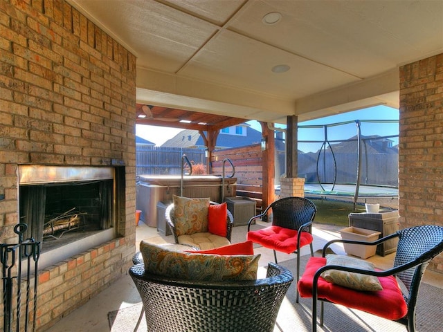 view of patio / terrace featuring a lanai, an outdoor living space with a fireplace, a hot tub, and fence