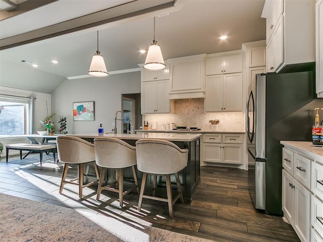 kitchen with a kitchen breakfast bar, dark wood-style floors, freestanding refrigerator, light countertops, and decorative backsplash