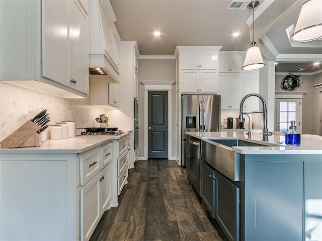 kitchen with premium range hood, a sink, hanging light fixtures, white cabinets, and crown molding