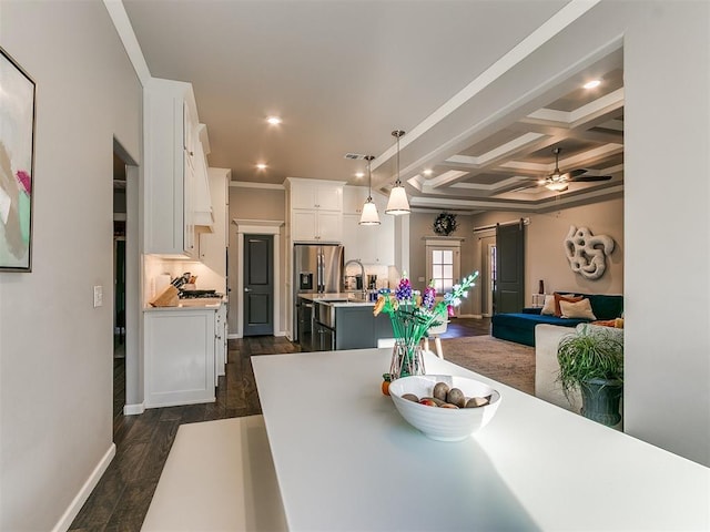 dining space featuring coffered ceiling, dark wood finished floors, beam ceiling, ceiling fan, and a barn door