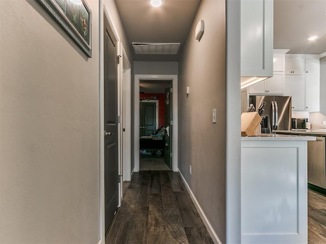 hallway with visible vents, baseboards, and dark wood-style floors