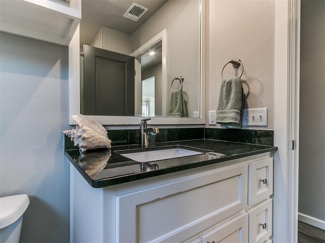 half bathroom with visible vents, toilet, and vanity