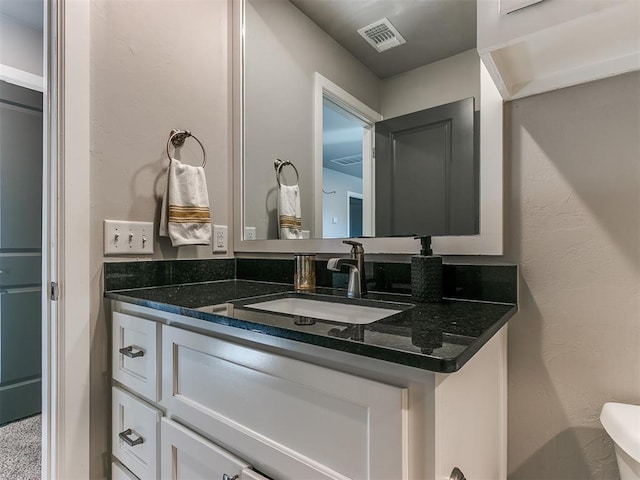 bathroom featuring visible vents, vanity, and a textured wall