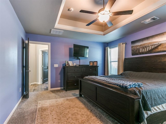 bedroom with visible vents, light colored carpet, baseboards, and a tray ceiling