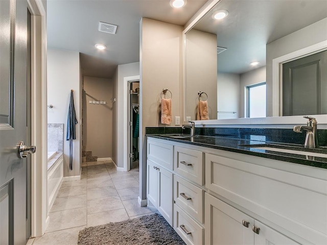 full bathroom featuring visible vents, double vanity, a sink, a spacious closet, and tile patterned floors