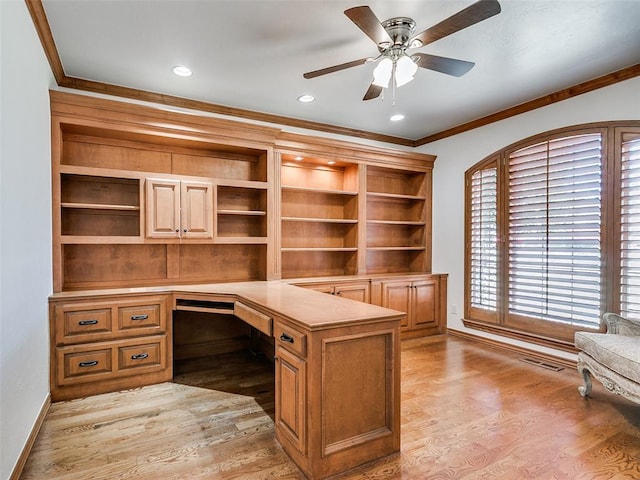 unfurnished office with light wood finished floors, ornamental molding, built in study area, ceiling fan, and baseboards