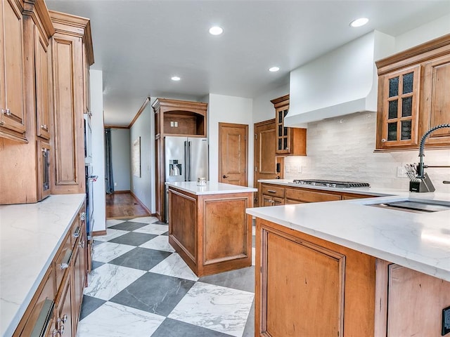 kitchen featuring recessed lighting, backsplash, brown cabinetry, a sink, and premium range hood