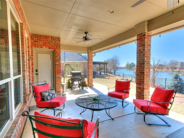 view of patio featuring a water view, fence, and ceiling fan