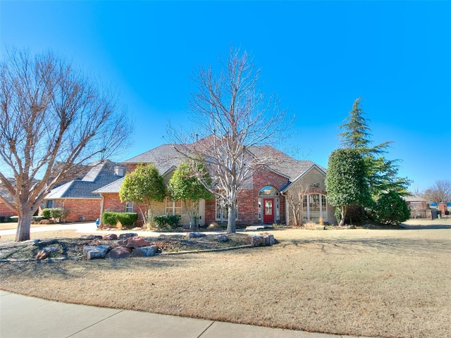 view of front facade with brick siding and a front lawn