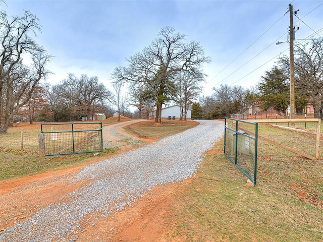 view of street with driveway, a gated entry, and a gate