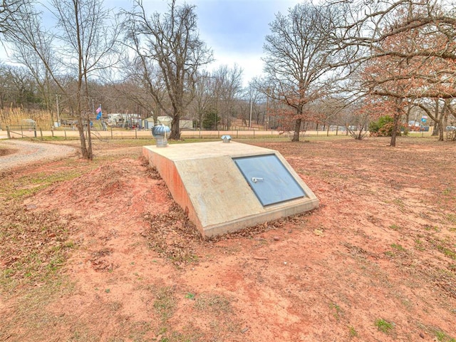 entry to storm shelter featuring fence