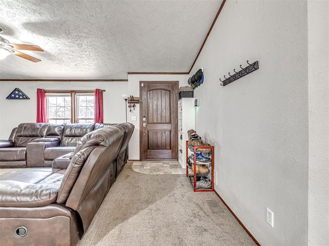 living room featuring a textured ceiling, a textured wall, ceiling fan, light carpet, and ornamental molding