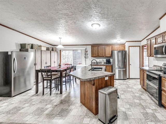 kitchen featuring brown cabinets, crown molding, appliances with stainless steel finishes, stone finish floor, and a sink