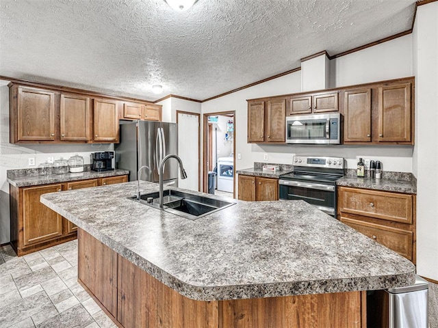 kitchen featuring a kitchen island with sink, stainless steel appliances, a sink, brown cabinetry, and crown molding