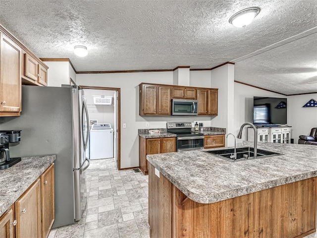 kitchen with a sink, appliances with stainless steel finishes, stone finish floor, washer / dryer, and crown molding