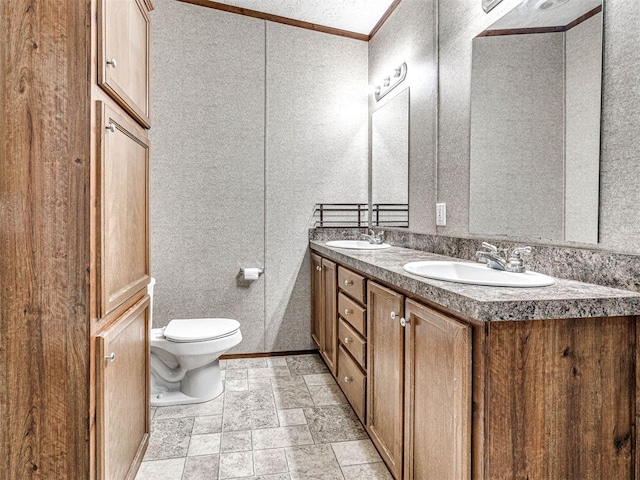 bathroom with toilet, stone tile flooring, double vanity, and a sink