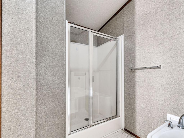 bathroom with a shower stall and a textured ceiling