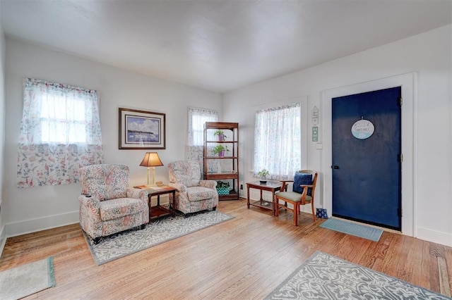 sitting room featuring baseboards, a healthy amount of sunlight, and wood finished floors