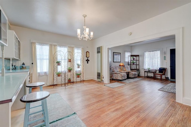 entrance foyer featuring light wood-type flooring, baseboards, a wealth of natural light, and a chandelier