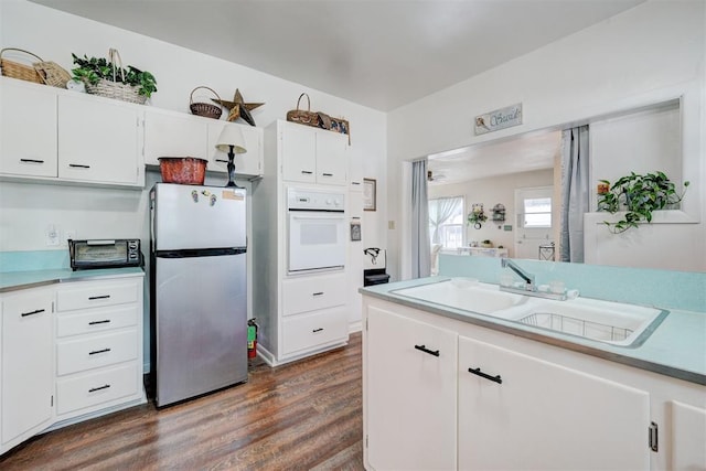 kitchen featuring white cabinets, oven, freestanding refrigerator, and dark wood-style flooring