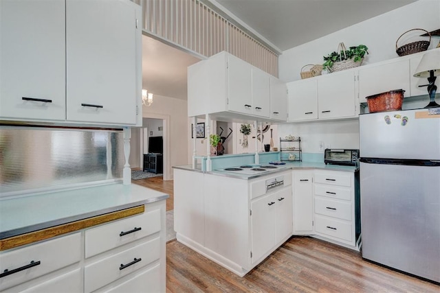 kitchen with light countertops, freestanding refrigerator, light wood-style flooring, and white cabinets