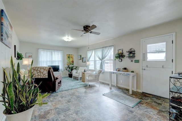 interior space with a wealth of natural light, stone finish flooring, and ceiling fan