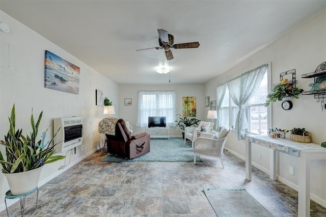 living room featuring ceiling fan, stone finish flooring, baseboards, and heating unit