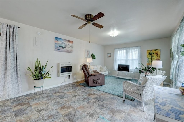 living area with ceiling fan, stone finish flooring, baseboards, and heating unit