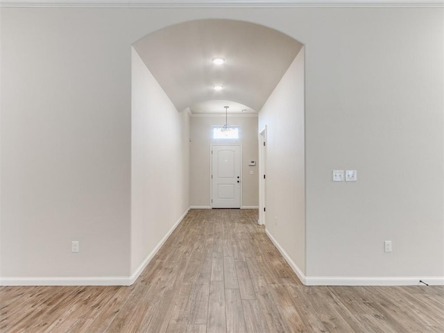 interior space featuring baseboards, arched walkways, and wood finished floors