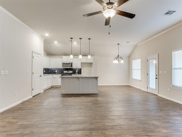 kitchen featuring lofted ceiling, stainless steel appliances, visible vents, open floor plan, and ornamental molding