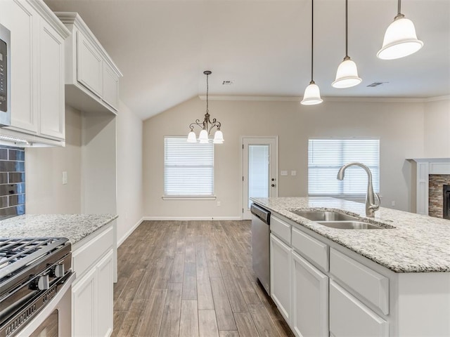 kitchen with a fireplace, wood finished floors, a sink, white cabinetry, and a wealth of natural light