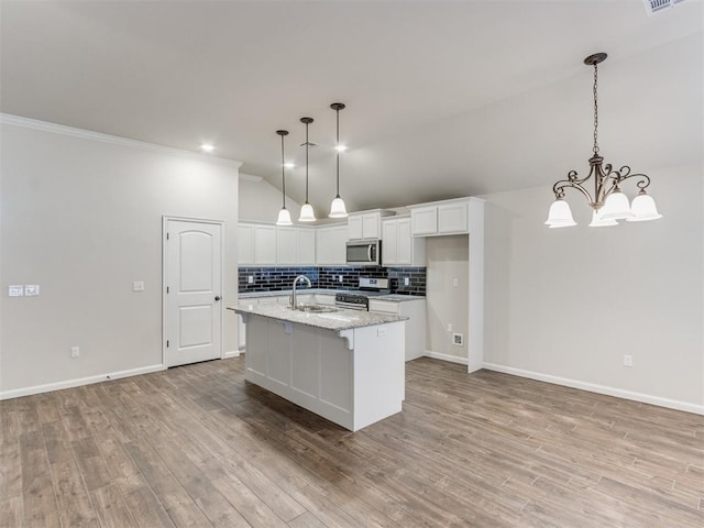 kitchen featuring tasteful backsplash, lofted ceiling, appliances with stainless steel finishes, white cabinets, and a sink