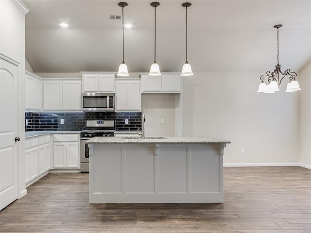 kitchen with tasteful backsplash, appliances with stainless steel finishes, vaulted ceiling, and a sink