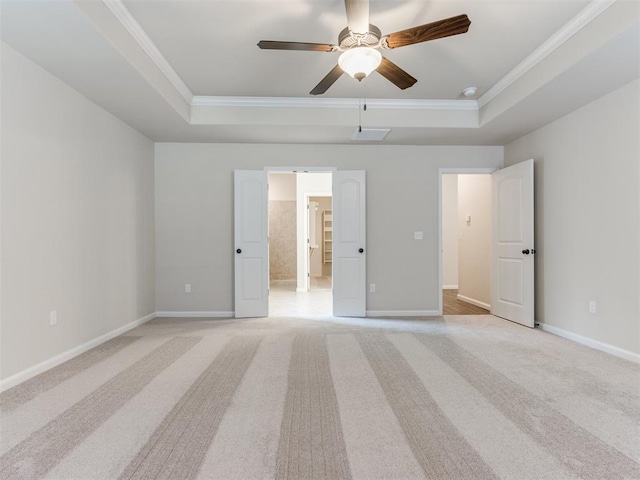 unfurnished bedroom featuring baseboards, a tray ceiling, ornamental molding, and light colored carpet