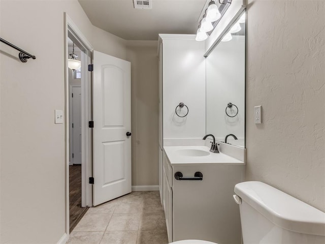 bathroom featuring a textured wall, toilet, visible vents, vanity, and tile patterned floors