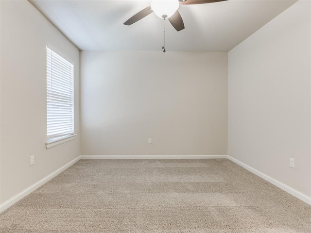 carpeted empty room with ceiling fan, a wealth of natural light, and baseboards