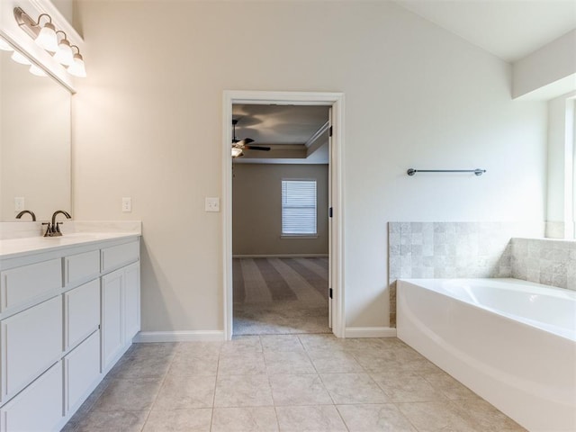 bathroom featuring ceiling fan, tile patterned flooring, vanity, baseboards, and a bath