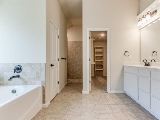 bathroom featuring tile patterned floors, a spacious closet, a tile shower, vanity, and a bath