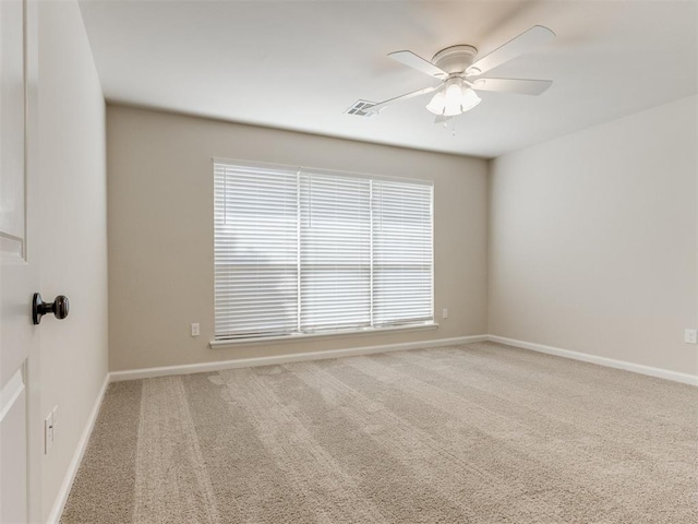 carpeted spare room with ceiling fan, visible vents, and baseboards