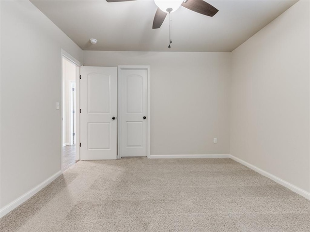 spare room with light colored carpet, ceiling fan, and baseboards